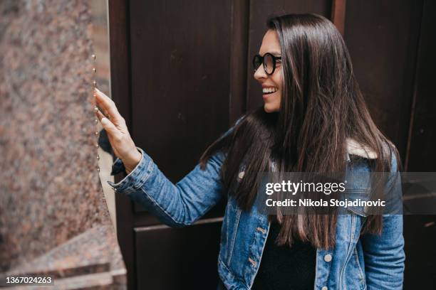 woman rings the doorbell of the building - deurbel stockfoto's en -beelden