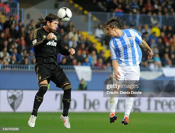 Sergio Ramos of Real Madrid heads the ball before Sebastian Fernandez of Malaga during the round of 16 Copa del Rey second leg match between Real...