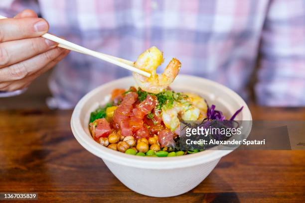 man eating poke bowl with shrimps, tuna and salmon, close-up - shrimp edamame stock pictures, royalty-free photos & images