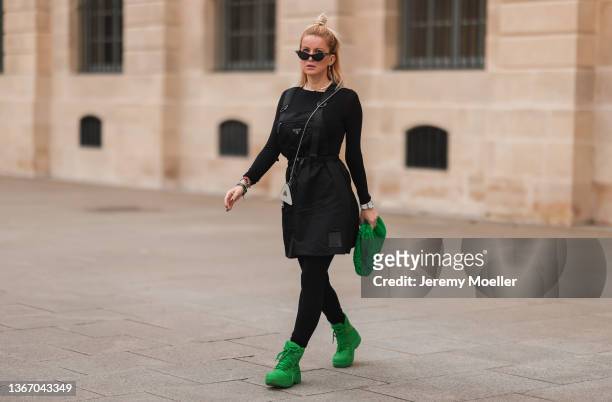 Palina Kozyrava is wearing a Prada Nylon black dress, mini Prada shiny silver bag, Bottega Veneta green pouch and matching Bottega Veneta green boots...