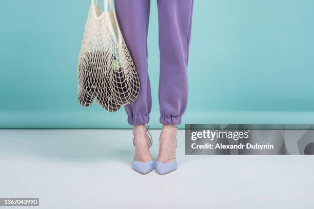 female legs and string bag with eggplant studio shot. - colorful shoes stock pictures, royalty-free photos & images