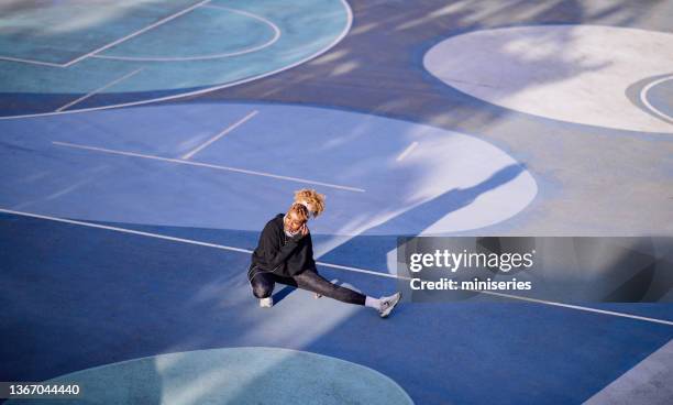 beautiful female athlete stretching on a basketball court - purple shoe 個照片及圖片檔