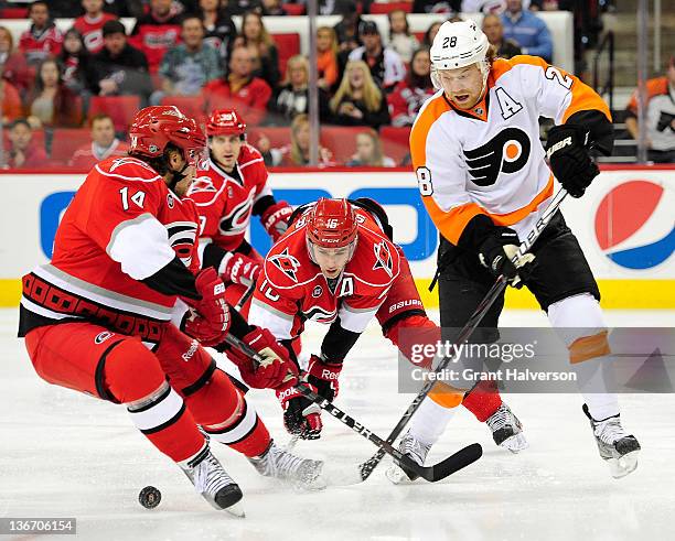 Andreas Nodl and Brandon Sutter of the Carolina Hurricanes knock the puck away from Claude Giroux of the Philadelphia Flyers during play at the RBC...