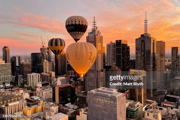 Hot air balloons are seen at sunrise flying over Melbourne CBD on January 24, 2022 in Melbourne, Australia.