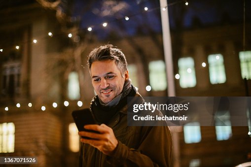 Homme d’âge moyen vérifiant son téléphone portable dans la rue Homme d’âge moyen vérifiant son téléphone portable dans la rue