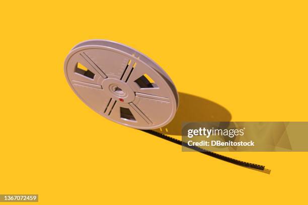 roll of 8 mm celluloid film, on yellow background. concept of cinema, film industry, movies, retro and vintage. - arclight theaters hollywood stock pictures, royalty-free photos & images