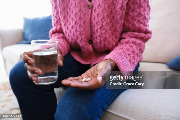 woman holds capsules and glass of water - moving activity stock pictures, royalty-free photos & images