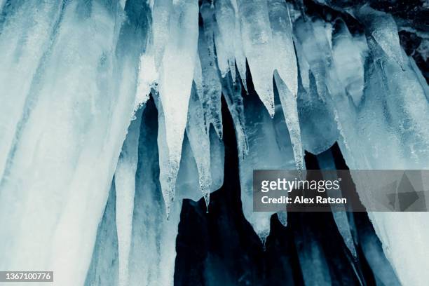 low angle view of large icicles hanging from the roof of an ice cave - spike stock pictures, royalty-free photos & images