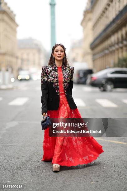 Heart Evangelista wears a gold flowers with red pearls embroidered metallic head band, silver earrings, a black with gold / pink / green embroidered...