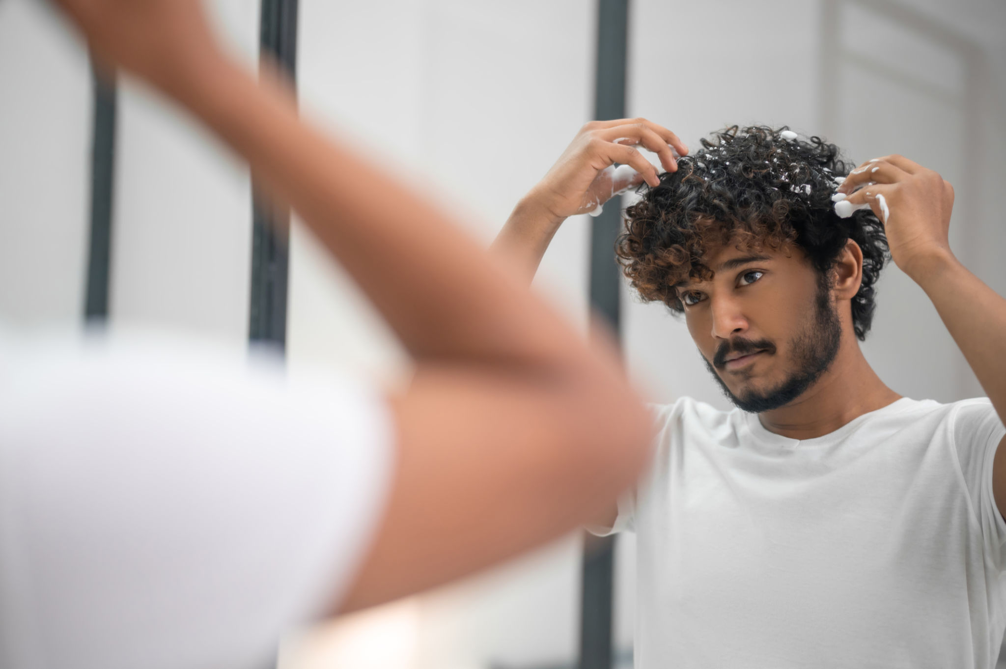 Macho esfregando o produto penteado em seus cachos Macho esfregando o produto penteado em seus cachos
