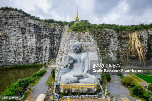 aerial drone view sunrise scene of stone buddha statue at wat khao tham thiam, suphanburi province, thailand. - province de suphanburi photos et images de collection