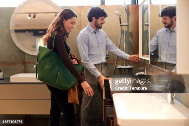 a couple is choosing a sink in a showroom. - renovation stock pictures, royalty-free photos & images