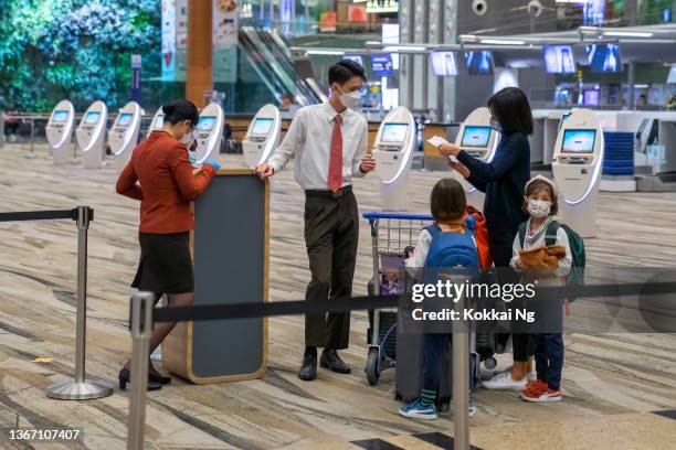 mulher com dois filhos falando com funcionários do solo no aeroporto de changi, cingapura - changi airport - fotografias e filmes do acervo