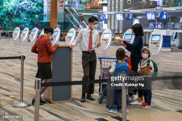 woman with two children talking to ground staff at changi airport, singapore - idrottsplatspersonal bildbanksfoton och bilder