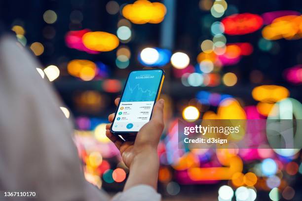 young woman using nft investment wallet on smartphone in illuminated city, working with blockchain technologies, investing nft on cryptocurrency, digital asset, art work and digital ledger. showing a downward trend on the trading in cryptocurrency market - cryptocurrency market stockfoto's en -beelden