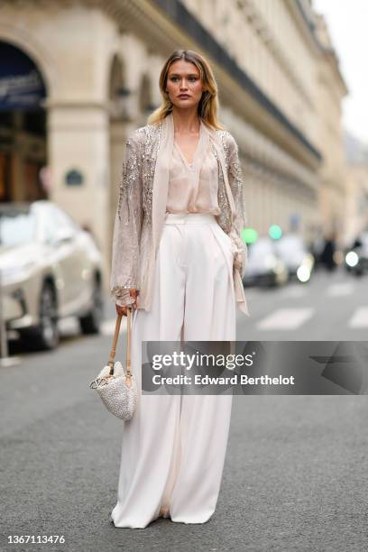 Chloe Lecareux wears a beige tulle with diamond embroidered pattern kimono / jacket, a beige transparent silk shirt, high waist white large flowing...