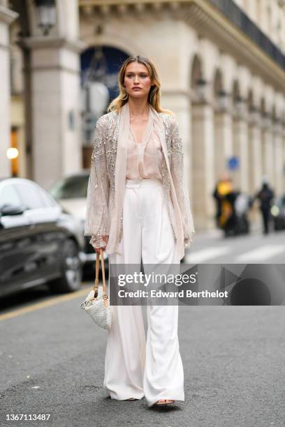 Chloe Lecareux wears a beige tulle with diamond embroidered pattern kimono / jacket, a beige transparent silk shirt, high waist white large flowing...