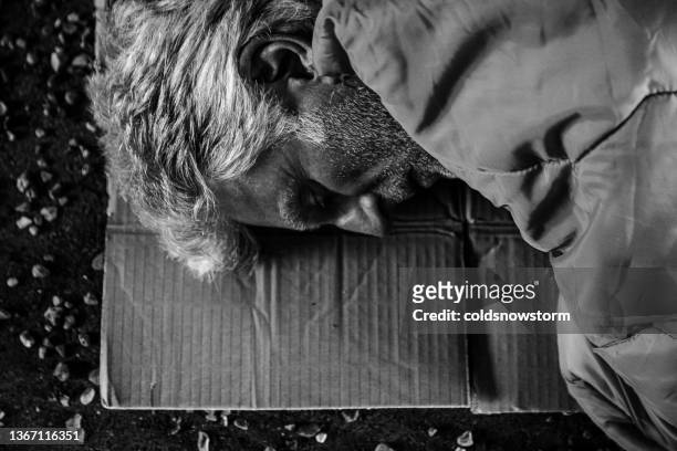 senior homeless man sleeping rough in dark tunnel - homeless person stockfoto's en -beelden