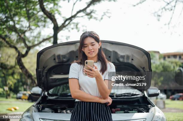 young asian woman waits for assistance near her car broken down on the road side - cars on motor way stockfoto's en -beelden