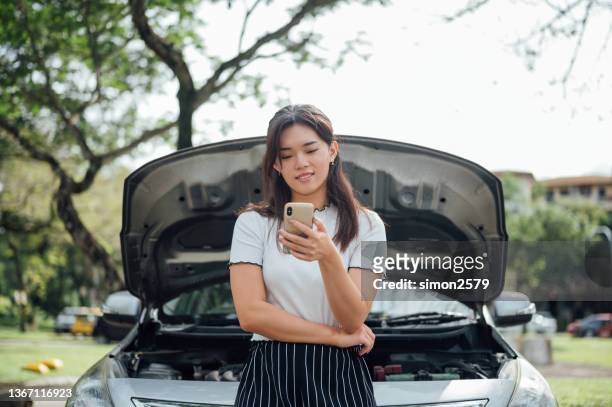 young asian woman waits for assistance near her car broken down on the road side - berma da estrada imagens e fotografias de stock