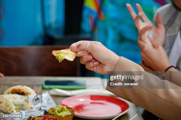 segurando um chip de tortilla com molho verde mergulhando na mesa em restaurante - dipping - fotografias e filmes do acervo