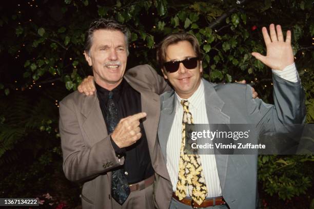 American actor Tom Skerritt points to American actor Beau Bridges, who has his right arm around Skerritt's shoulders while waving with left hand,...