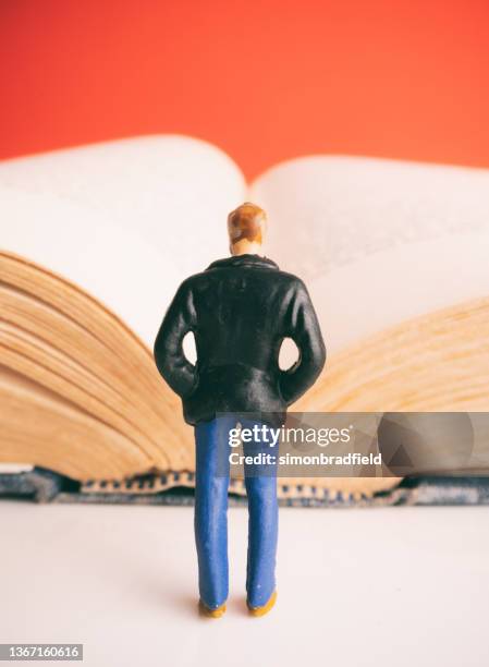 miniature man and an open book - beeldje stockfoto's en -beelden