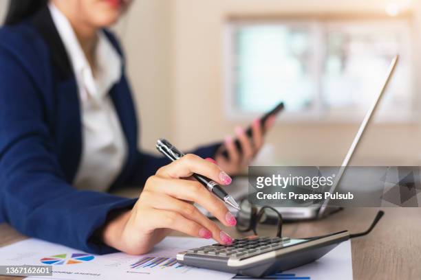 female financial advisor writing on diary while sitting with laptop at desk in office - accountants stockfoto's en -beelden