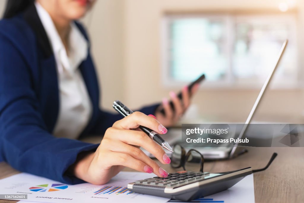 Female financial advisor writing on diary while sitting with laptop at desk in office