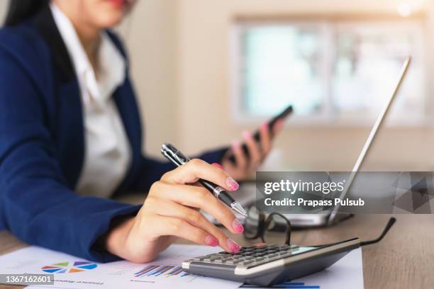 female financial advisor writing on diary while sitting with laptop at desk in office - accountancy 個照片及圖片檔