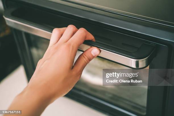 hand holding oven door handle. - handle stock-fotos und bilder