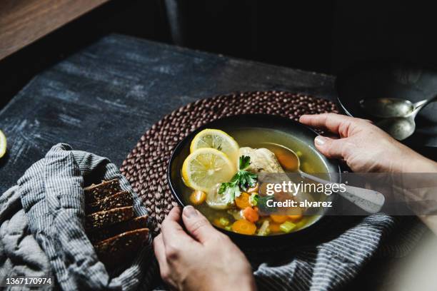 gros plan d’une femme servant un bouillon de poulet avec du pain complet - bouillon photos et images de collection