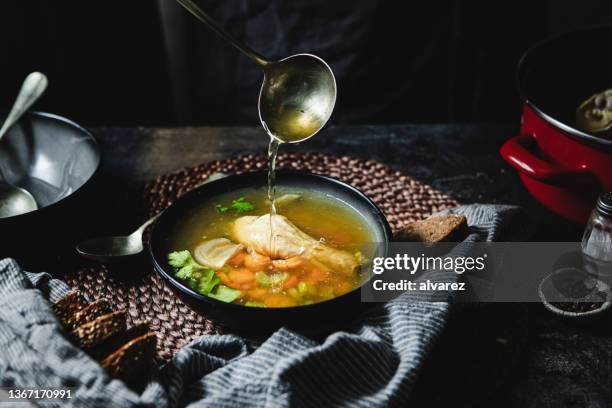 serving chicken broth in soup bowl - fond stockfoto's en -beelden
