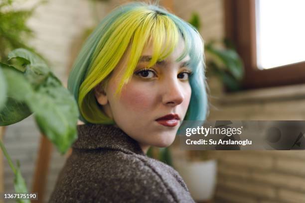 portrait of beautiful young woman with colorful hair and make-up together with plants - multi coloured hair stock pictures, royalty-free photos & images