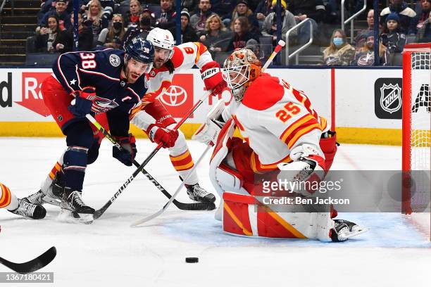 Goaltender Jacob Markstrom of the Calgary Flames defends the net as Boone Jenner of the Columbus Blue Jackets and Christopher Tanev of the Calgary...