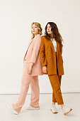 Stylish young women in pastel outfits standing together, fashion concept - stock photo