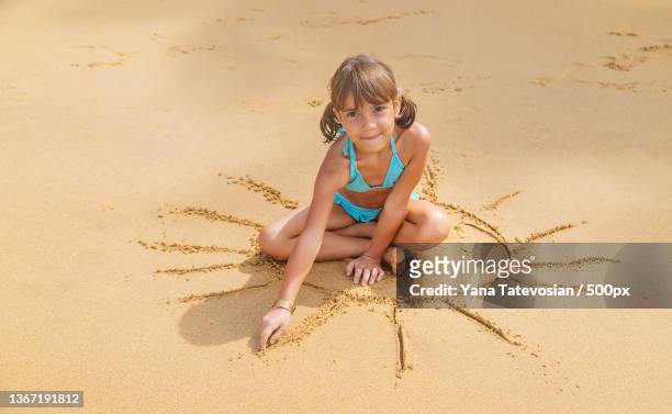 a child draws a sun on the beach selective focus - sandsun stock-fotos und bilder