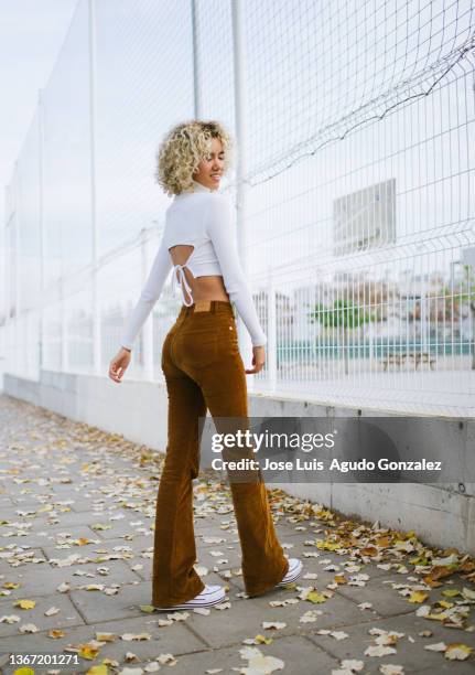 cheerful ethnic female walking on pavement - woman walks down street stock pictures, royalty-free photos & images