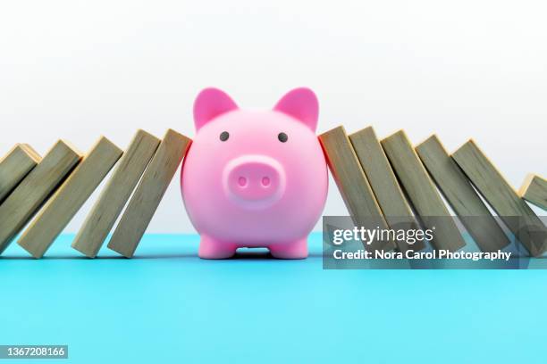 piggy bank with domino effect - financial stability concept - credit risk stock pictures, royalty-free photos & images