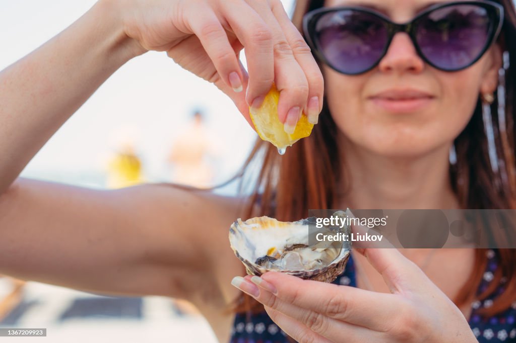 Oysters. A woman pours lemon juice on an oyster.