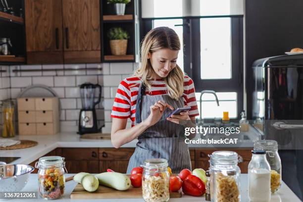 verticale d’une jeune femme utilisant le téléphone portable à la maison - recette photos et images de collection