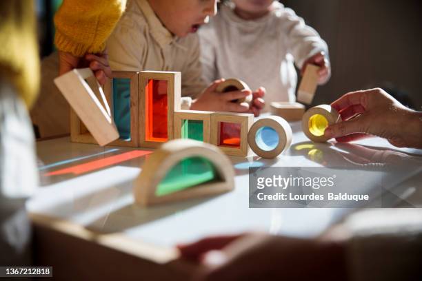 little kids playing with colorful wooden building blocks on the table - preschool building fotografías e imágenes de stock