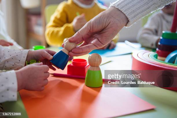 preschool children playing with colorful shapes - day care stock-fotos und bilder