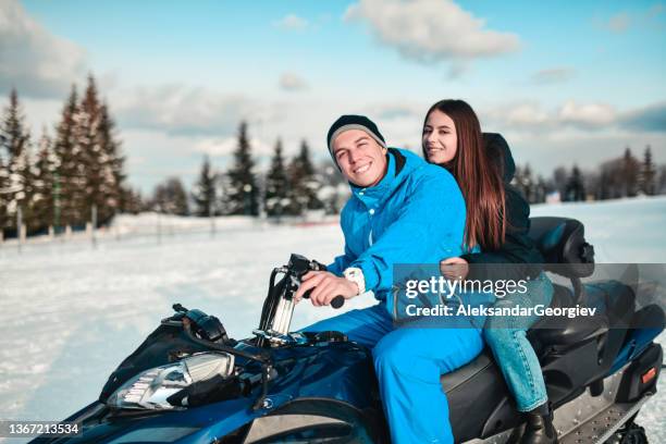 lächelndes paar, das die schneemobilfahrt auf dem berg genießt - snowmobiling stock-fotos und bilder