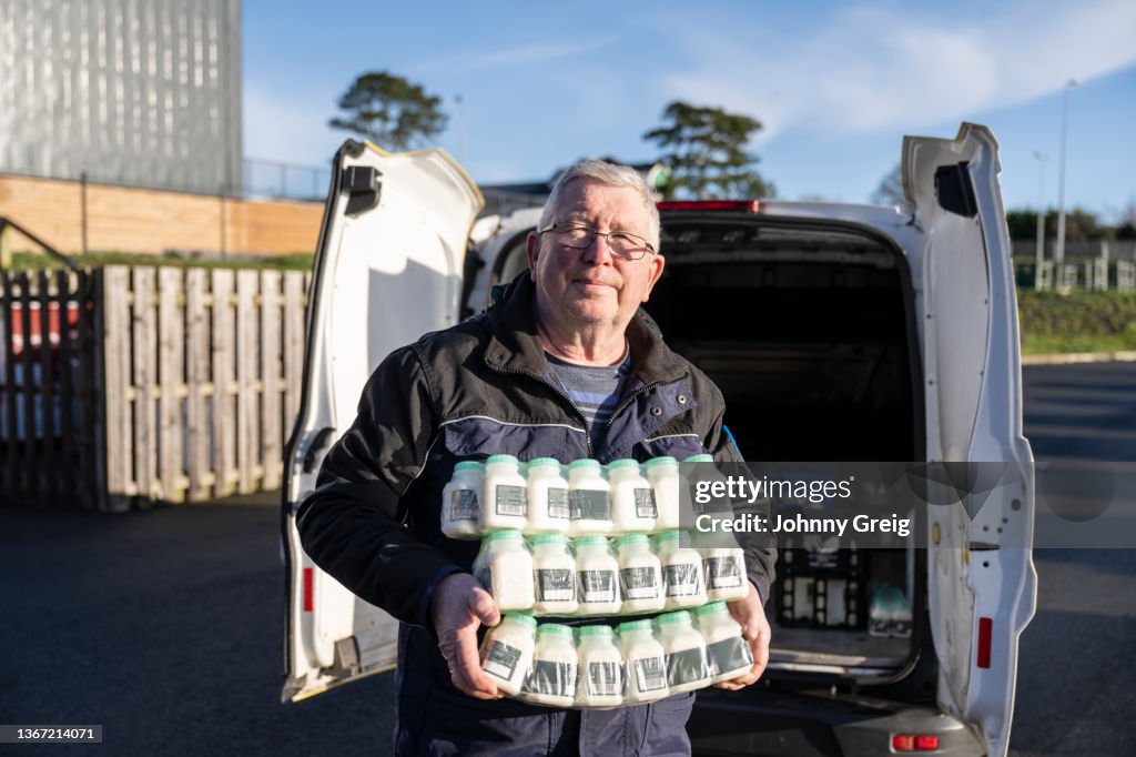 Portrait of milkman holding stack of milk containers