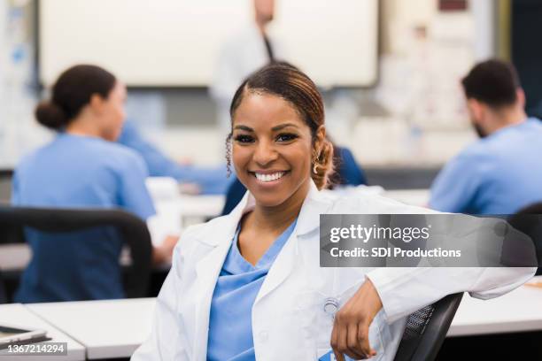 during lecture, female intern turns to smile for camera - portrait of teacher and student stockfoto's en -beelden