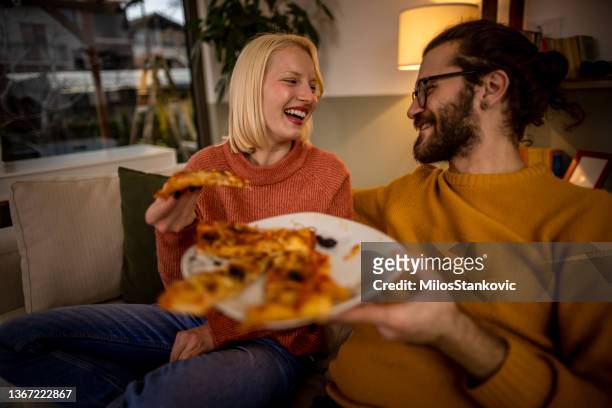 happy couple eating pizza at home - pizza share bildbanksfoton och bilder
