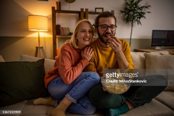 pareja viendo tv y comiendo palomitas de maíz - familia viendo tv fotografías e imágenes de stock