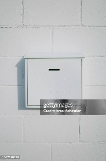 front view of a white post mailbox on a white brick wall. - letter box stock pictures, royalty-free photos & images