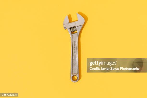 adjustable wrench on yellow background - verstellbarer schraubenschlüssel stock-fotos und bilder